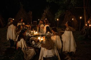 the yellowjackets in the woods wear white gowns and gather around a table in season 3