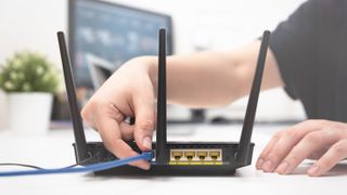 Woman connects an internet cable to the router