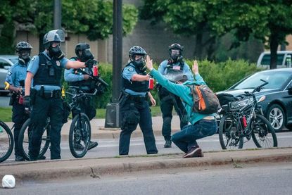 Minneapolis police officers spray a protester with a crowd control agent.