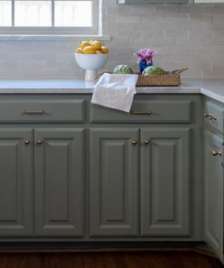 Green kitchen cabinets with bronze handles
