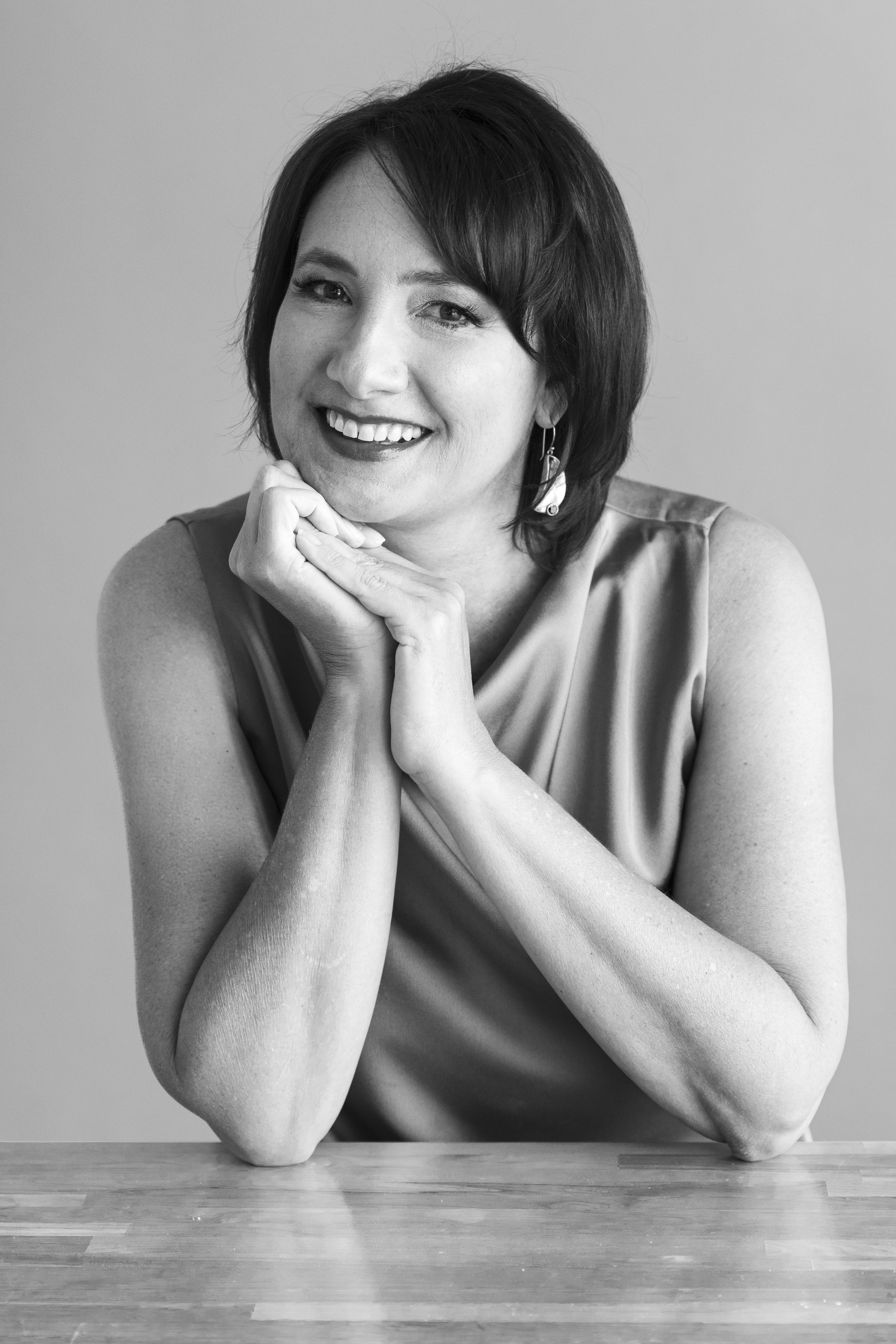 A black and white headshot of a woman with dark hair smiling at the camera