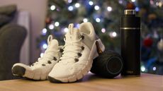 A pair nike shoes, a foam roller, and a water bottle on a table in front of a christmas tree