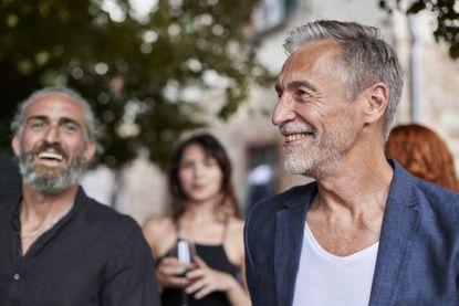 A happy older man relaxes with friends at an outdoor celebration.