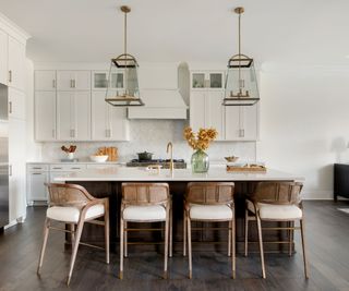 White modern kitchen with statement pendant lights and wooden rattan bar stools
