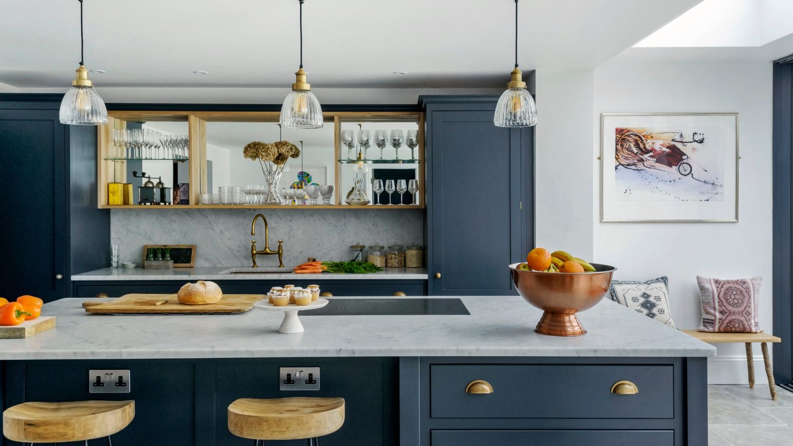 Kitchen island with dark blue kitchen units, grey marbled worktop and splash back. 
