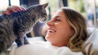 Woman laughing as cat gets up close to her face