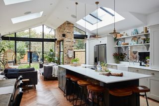 Open plan rear extension with Crittal-style floor-to-ceiling window, snug space, grey Shaker-style kitchen and black island, rooflights and industrial-style pendant lights and bar stools