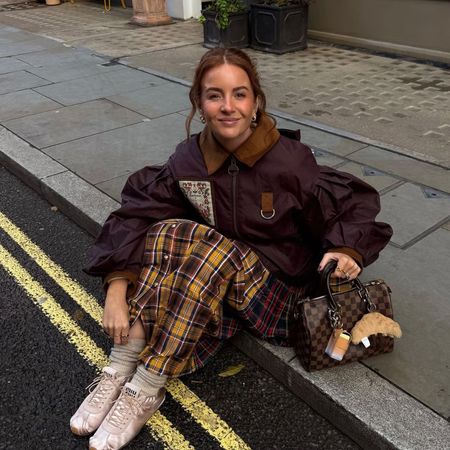 Influencer @rebeccaferrazwyatt sits on the pavement in London wearing a Louis Vuitton Speedy bah.