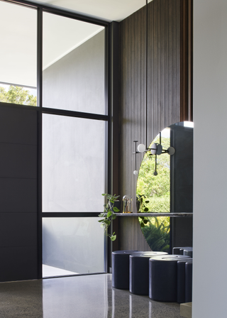 An entryway featuring a mini trailing plant, a large mirror and seating