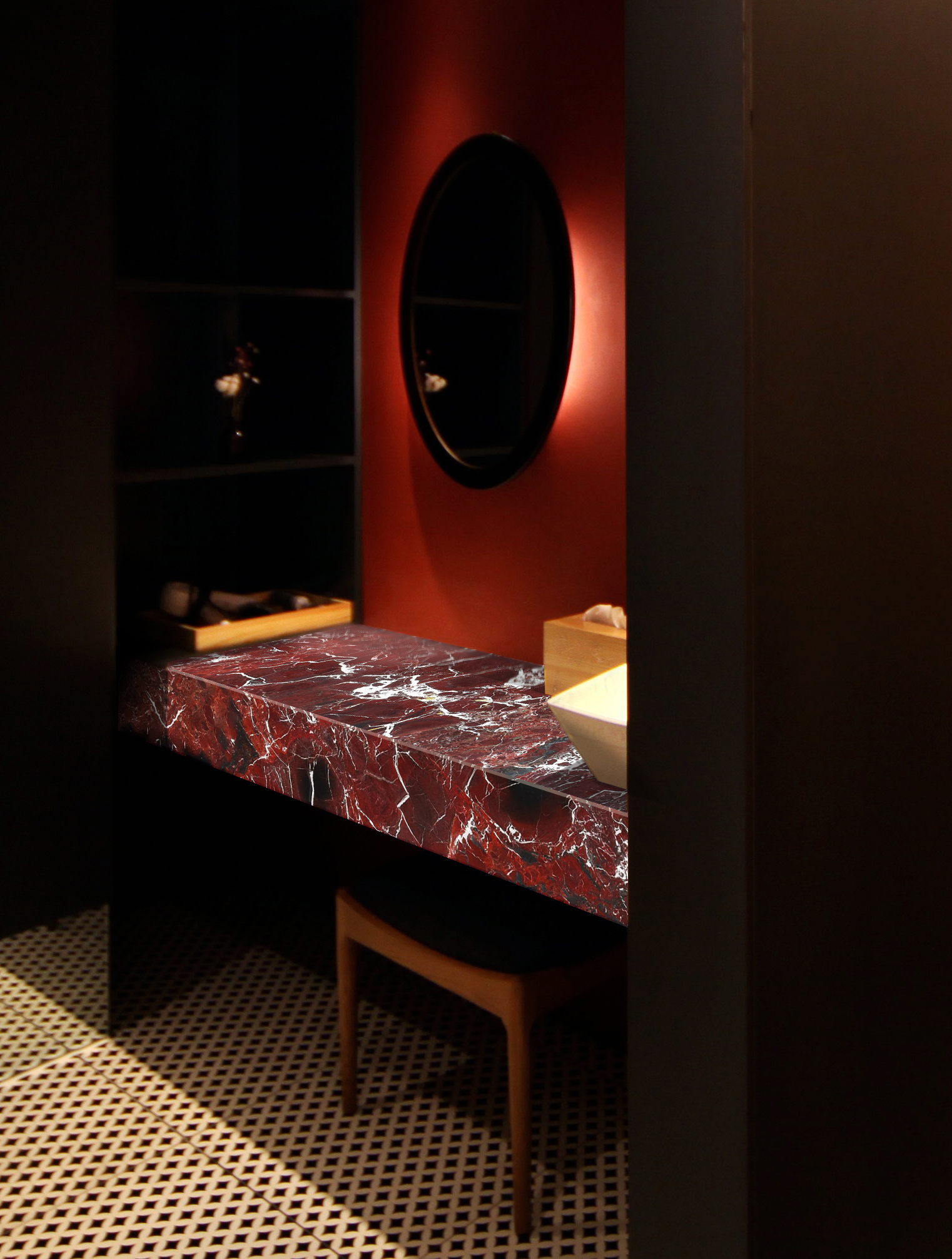 A dark bathroom with deep red walls, and a strongly veined red marble block as a dressing table surface, a wooden stool underneath and a diamond patterned black and ivory floor for added interest