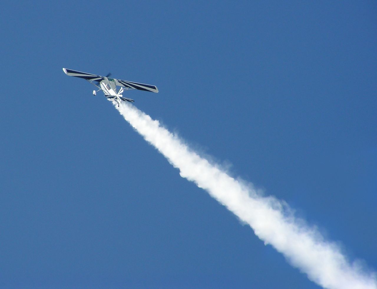 Plane with trail of smoke in sky.