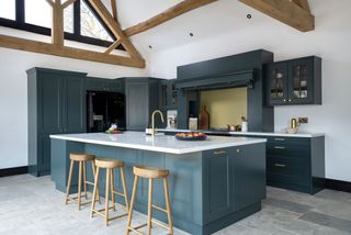 blue kitchen with white worktops with large island unit and white walls