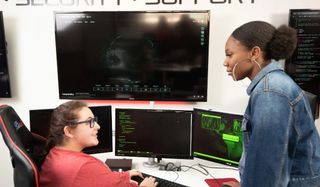 Two female students talk in cybersecurity lab