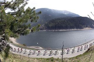 The peloton races past a lake in the Trentino region