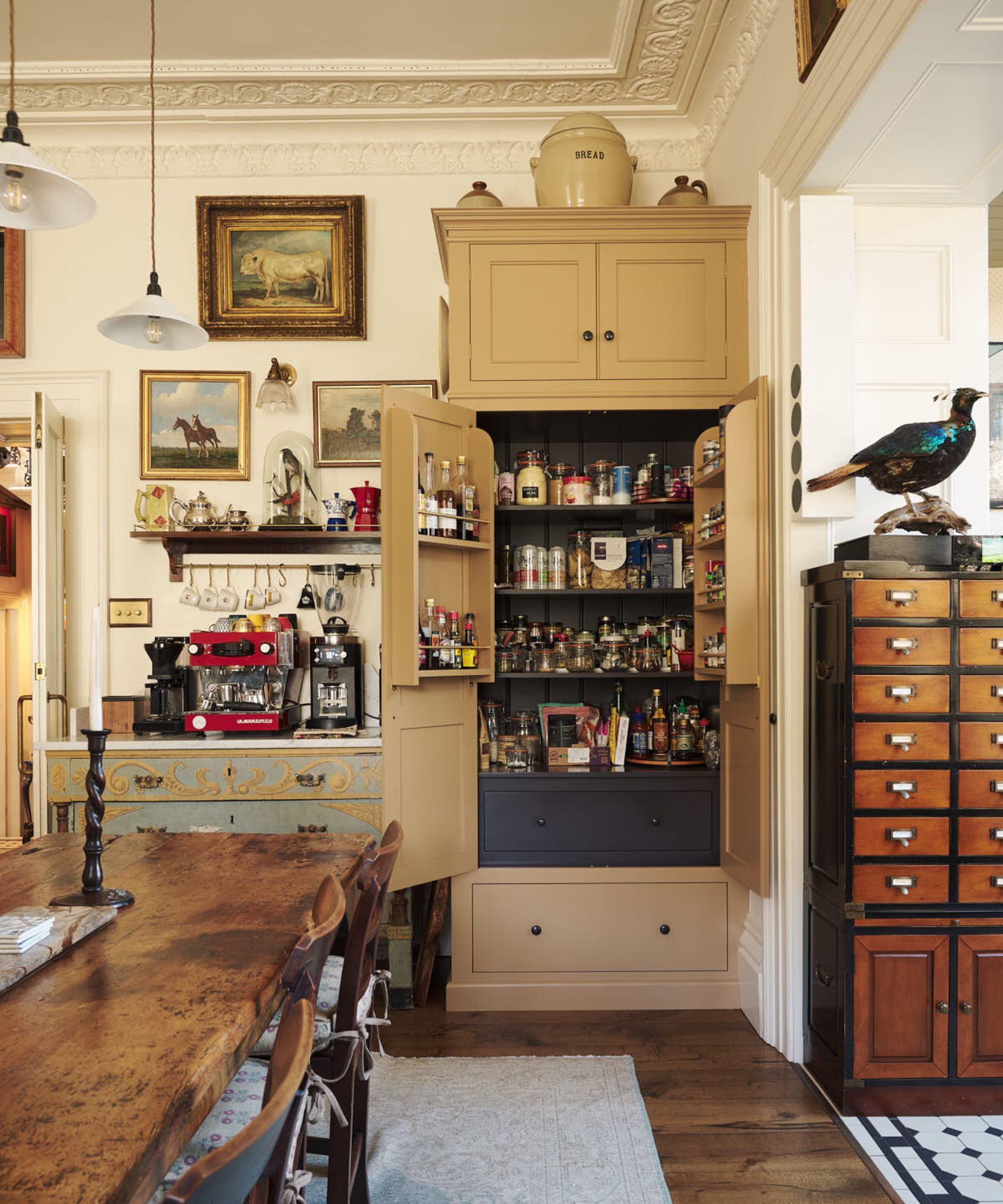 Traditional deVOL kitchen featuring a freestanding pantry cupboard with internal spice racks and drawer storage, set alongside a farmhouse dining table, antique furnishings and decorative wall art.