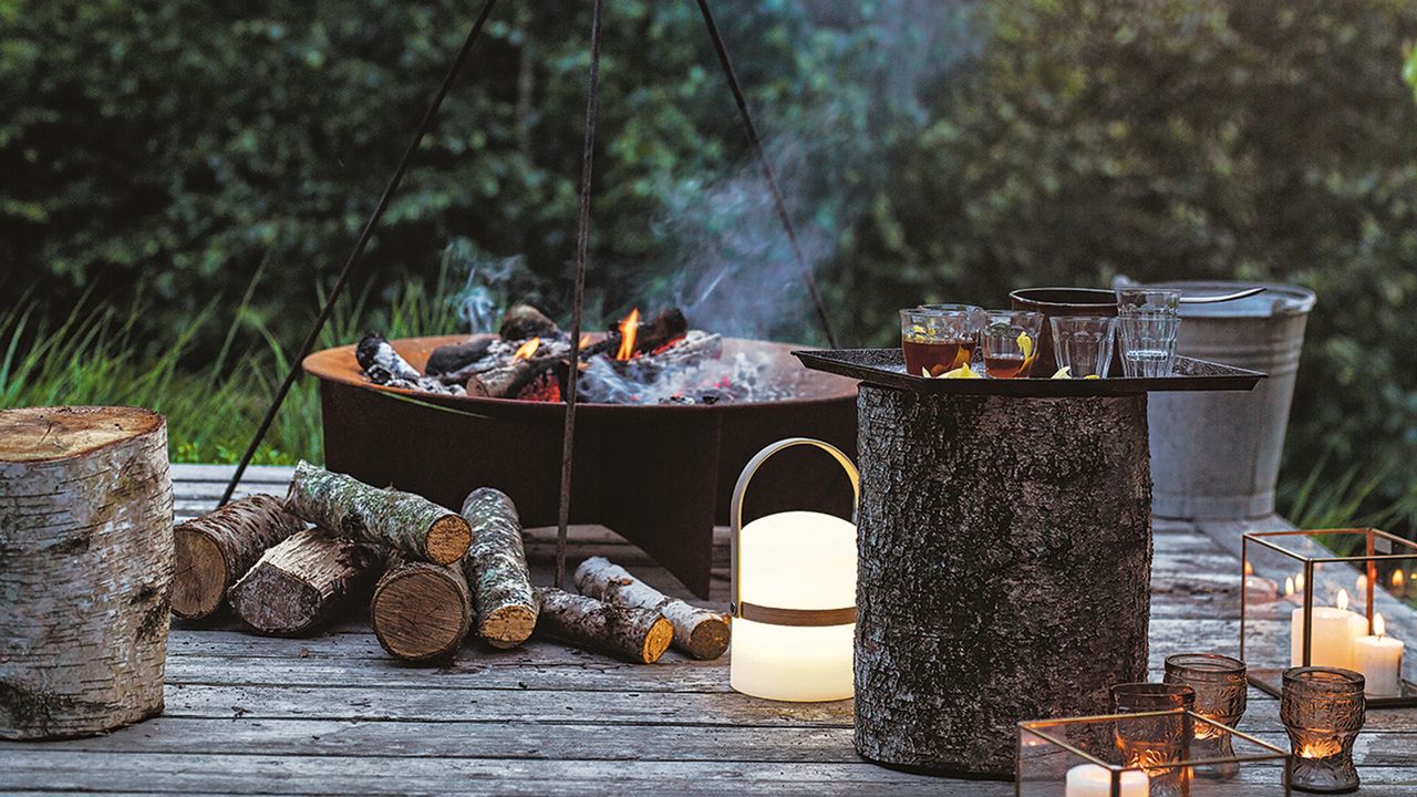 A deck in low light with a fire pit and glowing lanterns