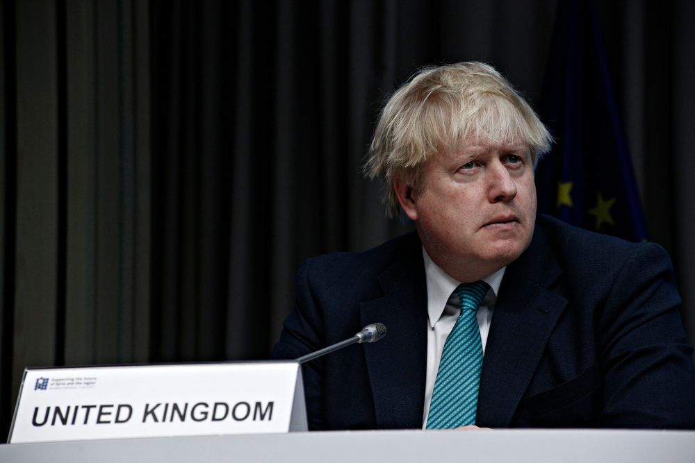 The prime minister, Boris Johnson, sitting on a panel in a dark room