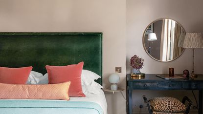 a bedroom with a green headboard and beige color walls