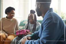 Parents giving teen daughter a present while sitting on the sofa at home