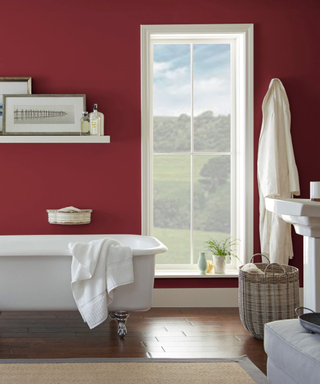 A crimson bathroom with a white freestanding bathtub.