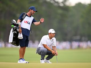 Tom Kim reading a putt, assisted by his caddie, at the US Open