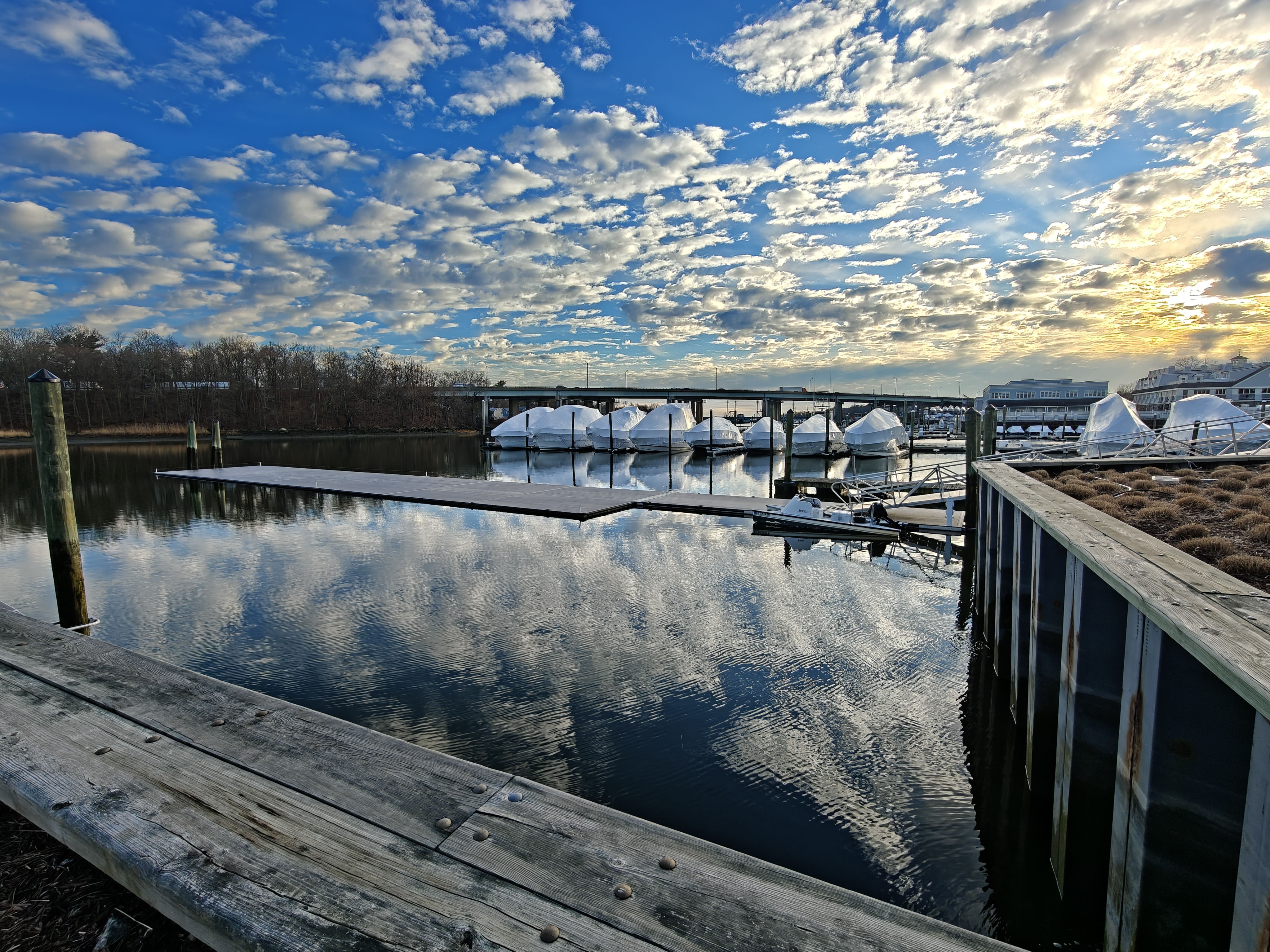 A sunset view of a river in Connecticut with fancy yachts wrapped for the winter season