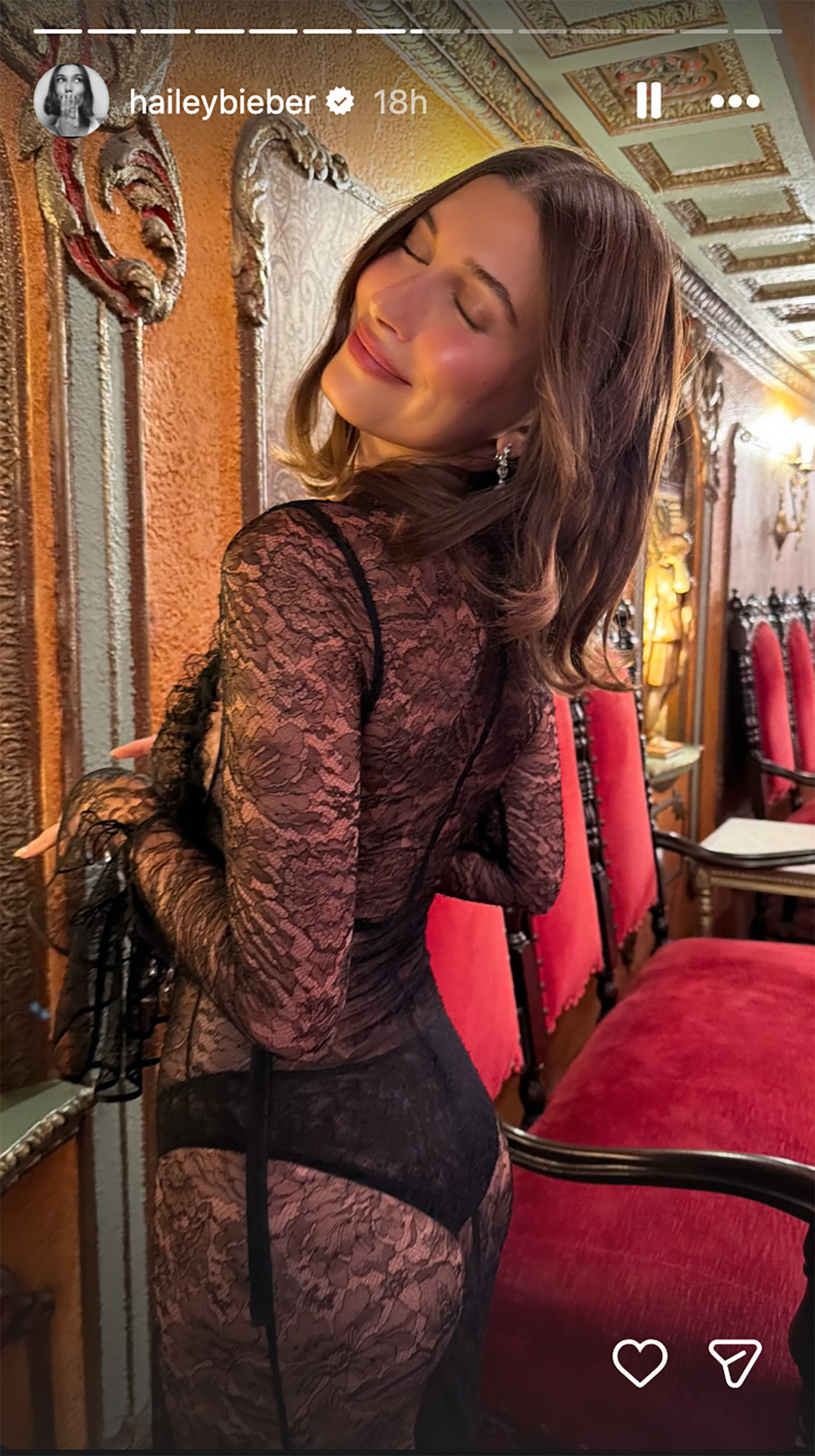 Hailey Bieber in a sheer black dress posing with her head thrown back.