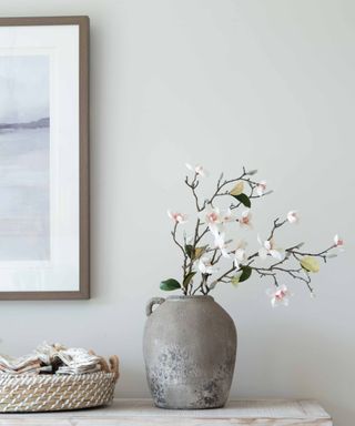 A gray vase with flowers in it on a table