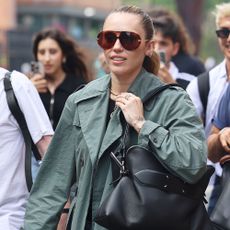 Miley Cyrus wearing a green trench coat and a black leather shoulder bag, and sunglasses