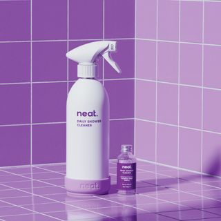 White spray bottle of Neat shower cleaner in a purple tiled shower