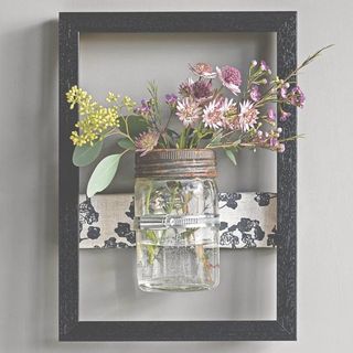 glass jar with flowers in it and black frame