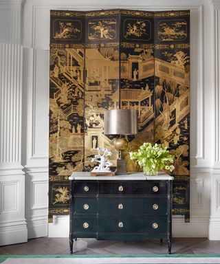 18th century Coromandel screen on wall and antique chest of drawers in Edwardian house in West London designed by Philip Vergeylen of Nicholas Haslam