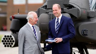 King Charles III and Prince William, Prince of Wales stand in front of an Apache helicopter