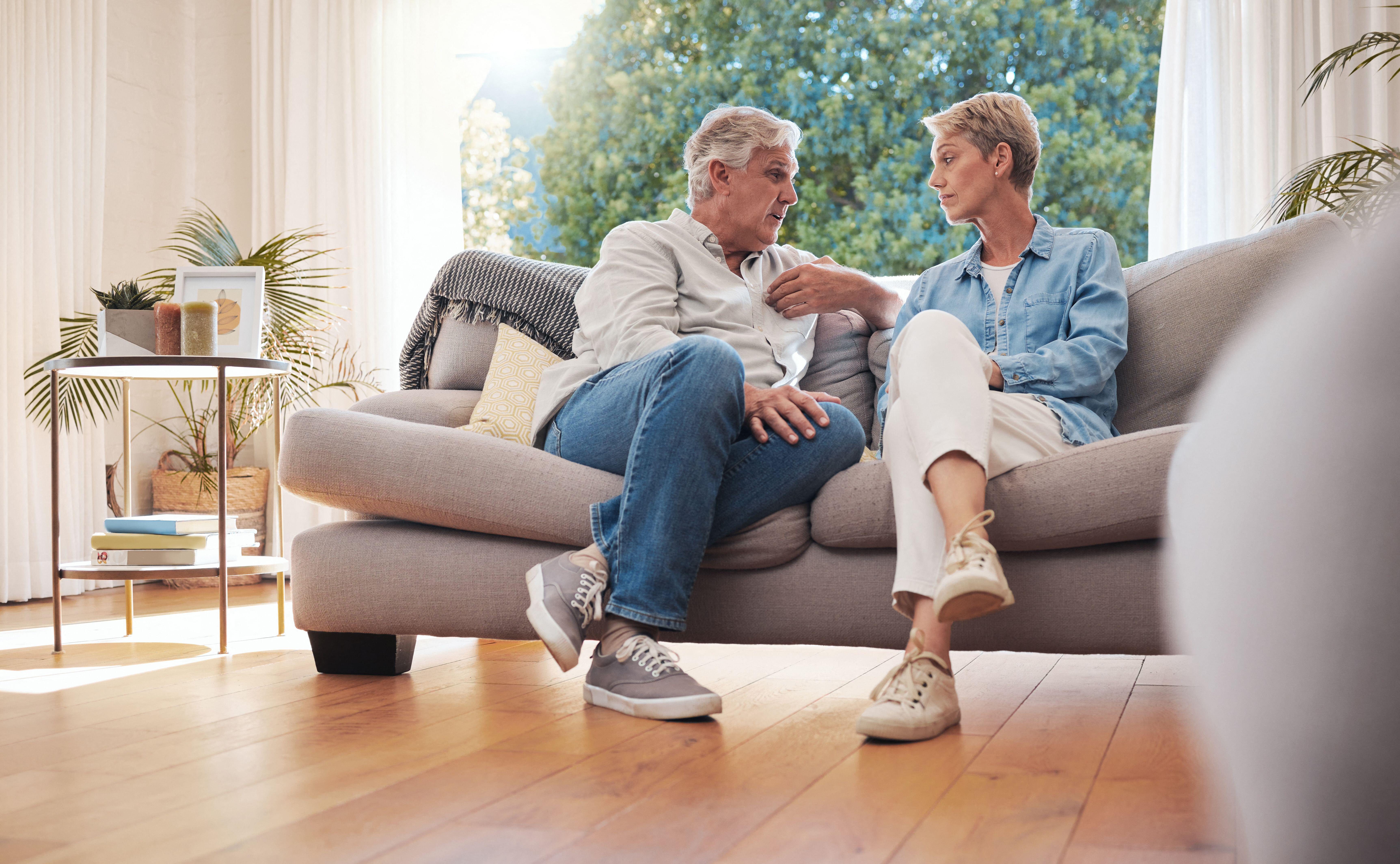 2K2NAWP Senior couple, serious talk and communication about problems and marriage issues while sitting on the sofa at home. Mature man and woman talking and