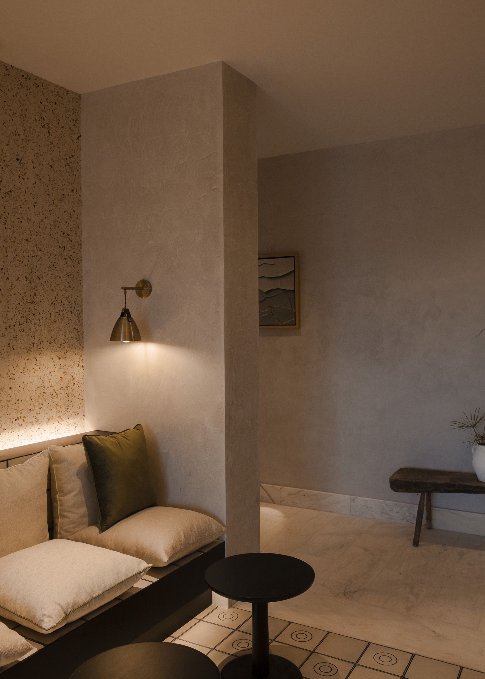 A waiting area with cushion seating, a table, and dim lighting. 