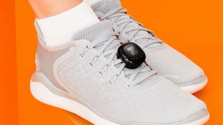 The Zwift Runpod in black attached to some white shoes on an orange background