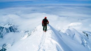 Climber on steep, exposed snowy summit of Europe&#039;s tallest peak, Mt Blanc