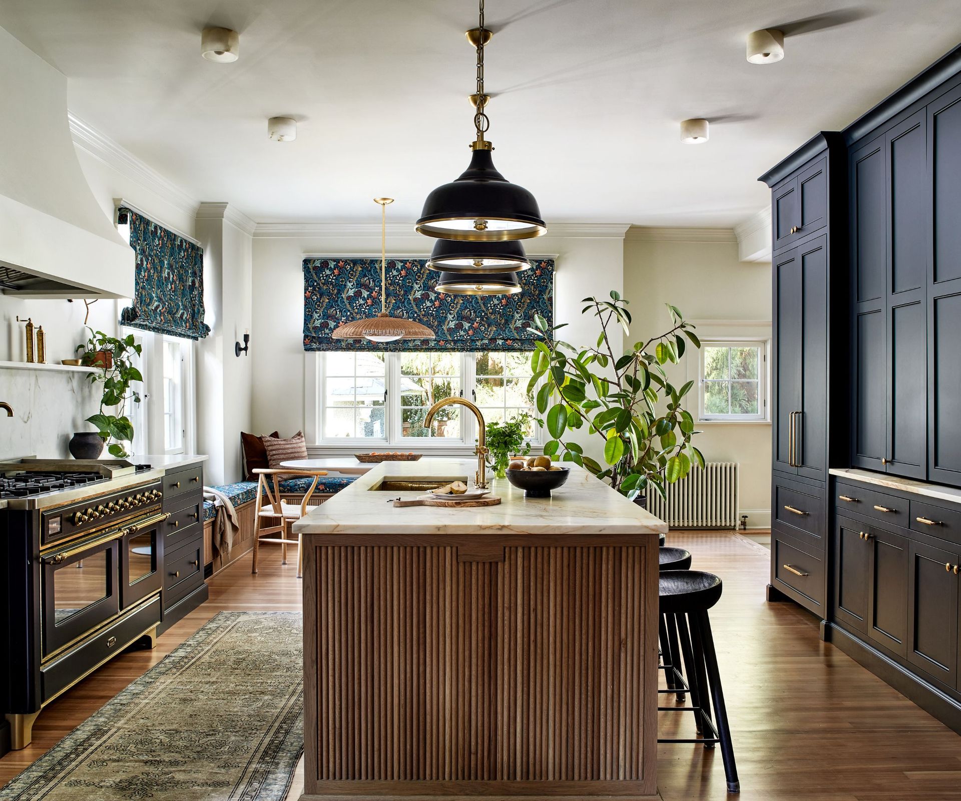 A kitchen with blue cabinets, white walls, a wooden island, and a cozy dining nook