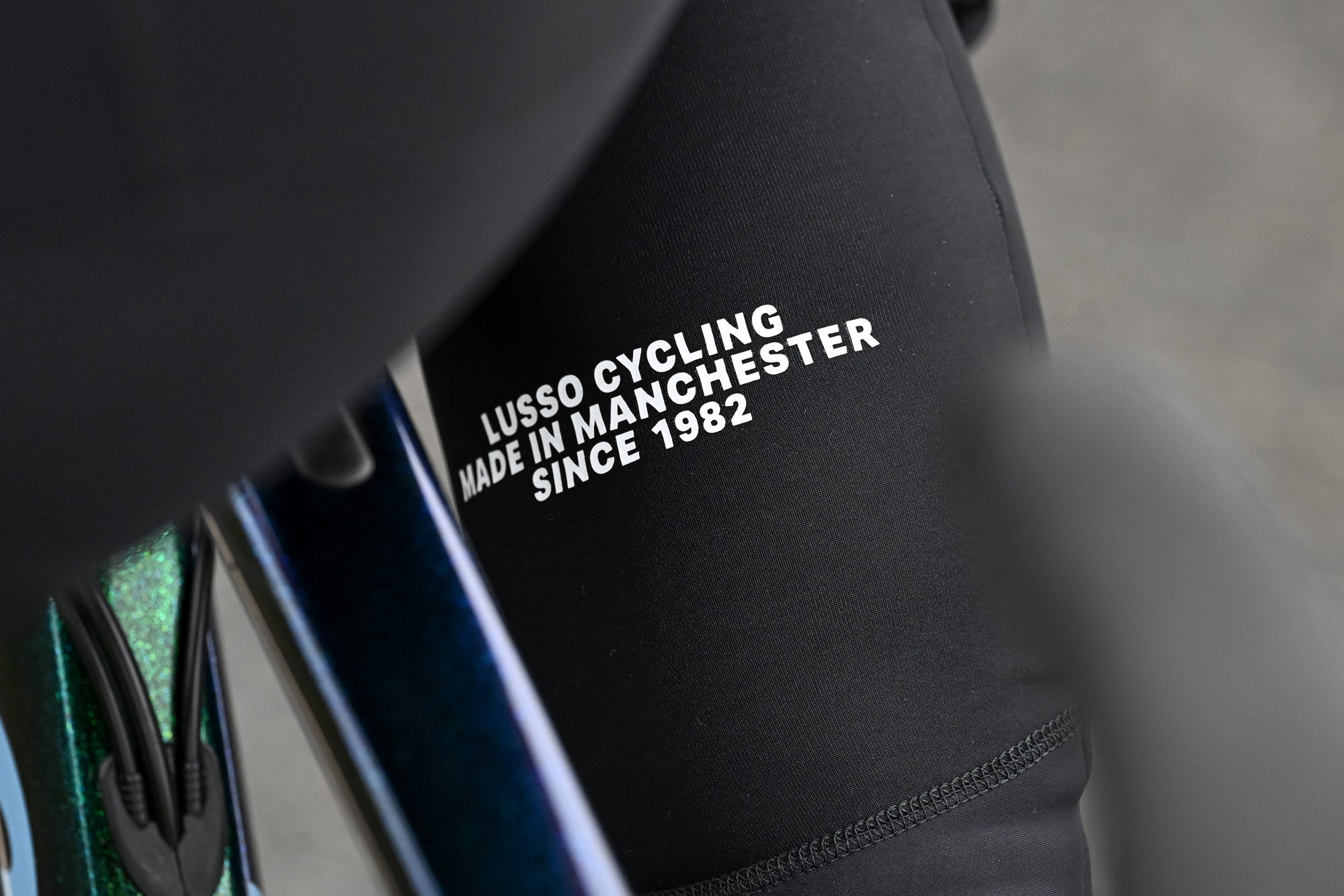Close up of text on the right calf of some black bib tights that says "Lusso Cycling made in Manchester since 1982"