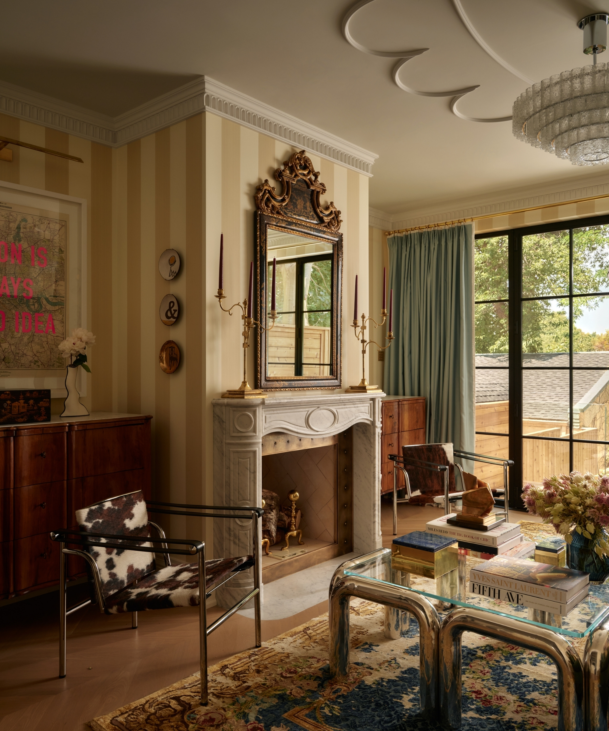 Living room with brass candlesticks, ceiling light and natural light beside a marble fireplace and blue curtains.