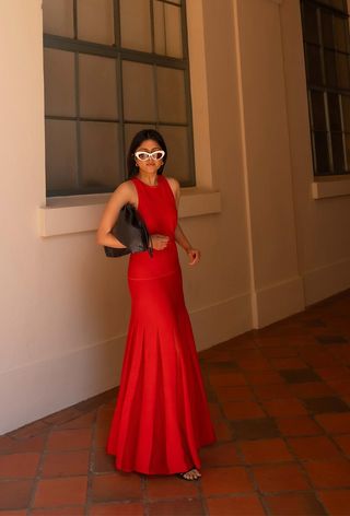a photo of a woman wearing a red maxi dress with black slide sandals