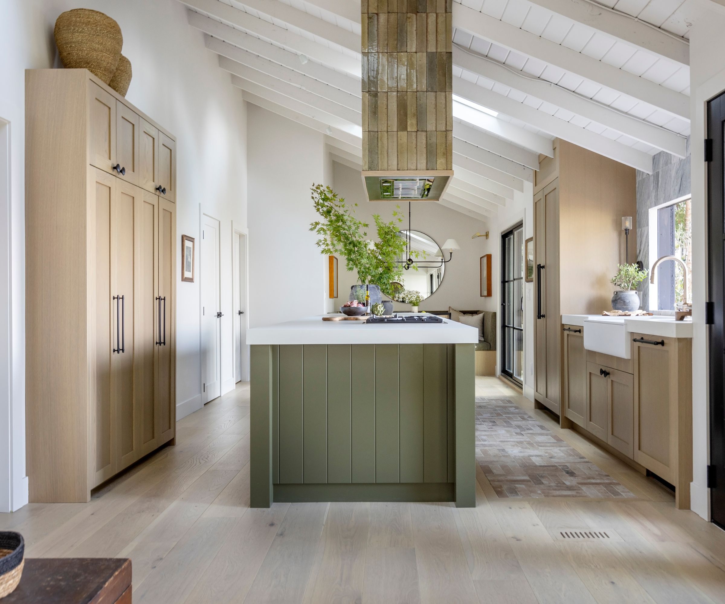 A large kitchen with wooden cabinets, a green island, and a ceiling mounted green tiled extractor fan above the island