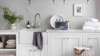 utility and laundry room with white cupboards and belfast sink