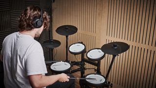 5 reasons why Black Friday is the best time to buy an electronic drum set: Man wearing headphones playing the Roland TD-07 electronic drum set.