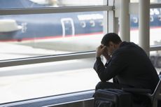 A man puts his head in his hands in frustration at the airport.