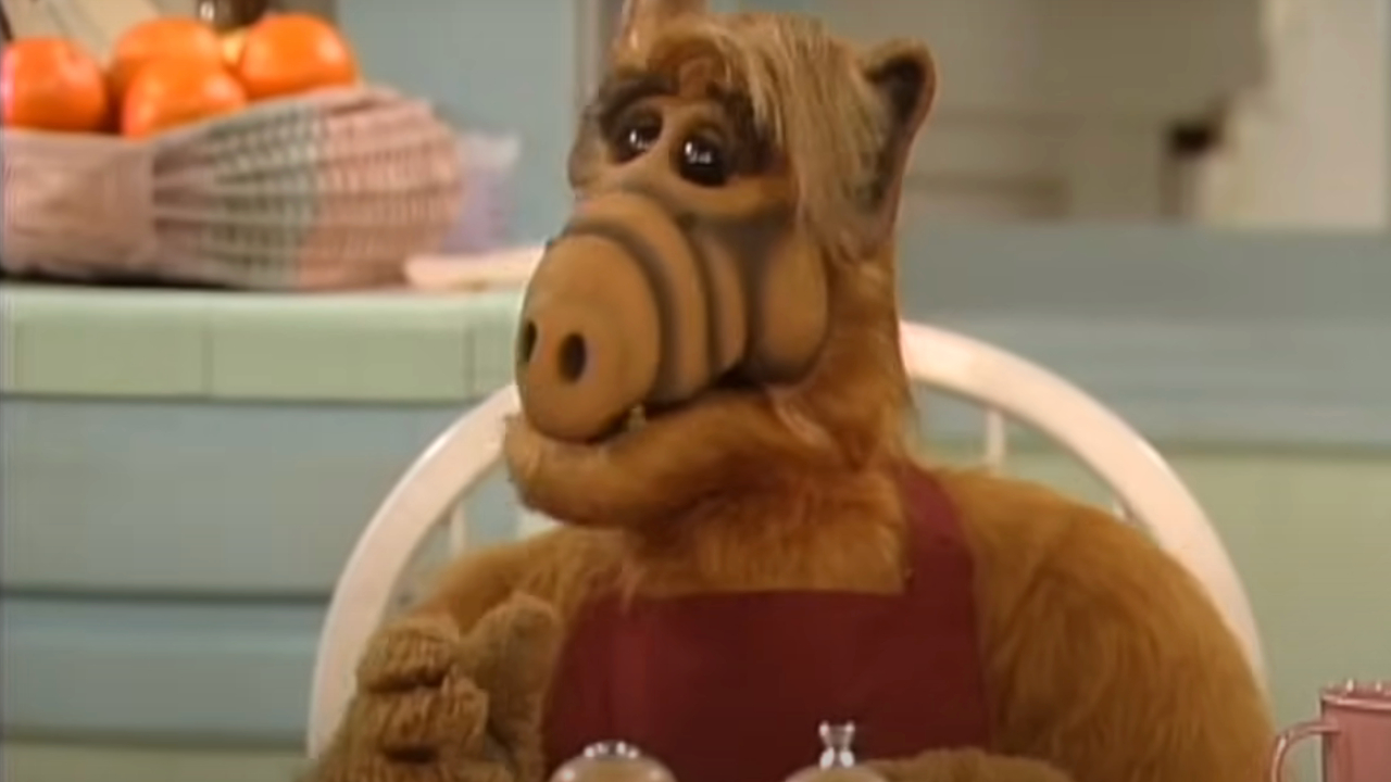 Alf sits at the kitchen table talking.