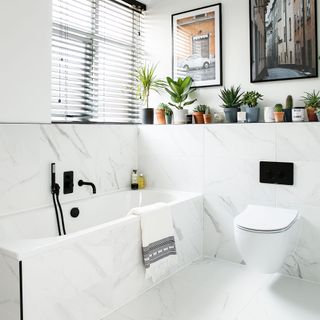 white marble bathroom with bathtub and potted plants