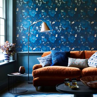 Living room with blue patterned wallpaper and orange velvet sofa