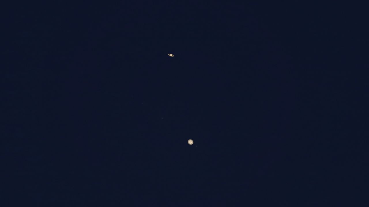A photo from a telescope showing Saturn and Jupiter in the night sky. Saturn's rings are visible.
