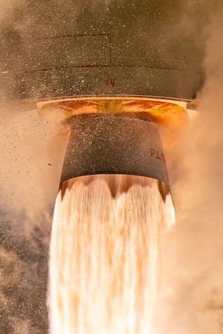 a massive plume of fire shoots out of a rocket engine